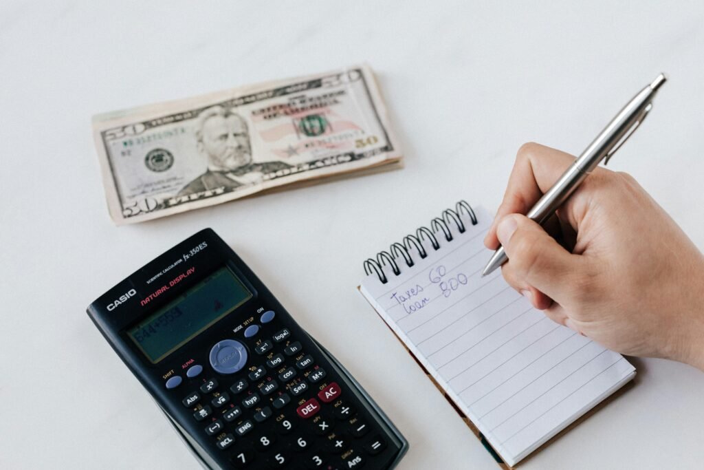 a man writing on jotter beside money and calculator is kept aside