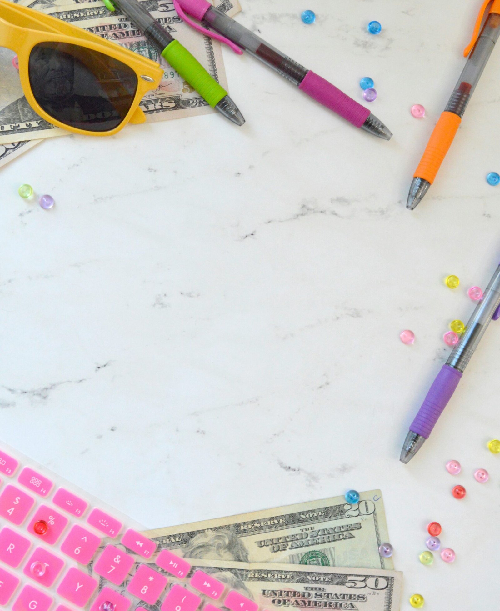 pink and white computer keyboard beside yellow framed sunglasses