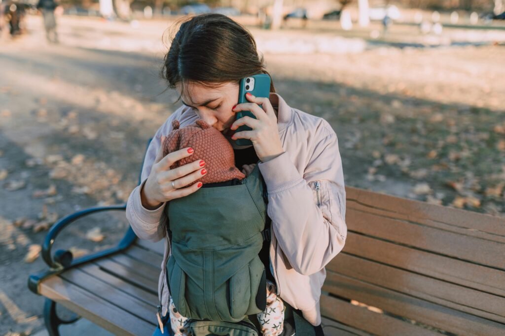 a woman holding her on a Baby Carrier working from home with a baby