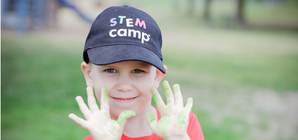 A young boy joyfully displays his hands covered in green paint, showcasing his creativity and artistic expression.