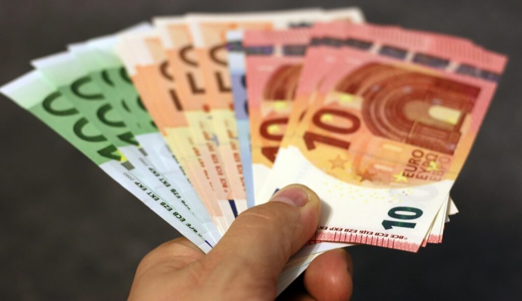 A hand is holding a stack of euro banknotes, showcasing various denominations in a clear and organized manner.